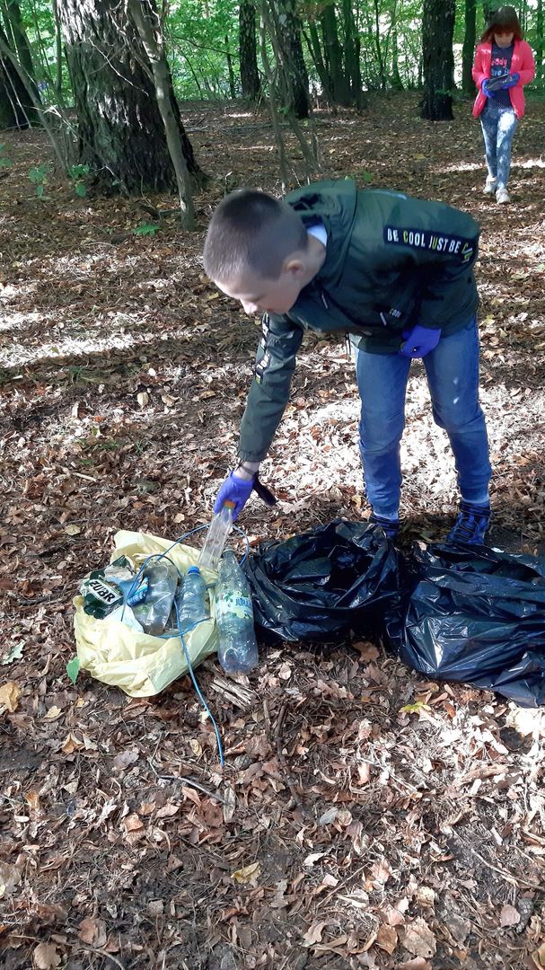 Uczeń ze Szkoły Podstawowej w Malechowie sprząta śmieci i wrzuca je do worka.