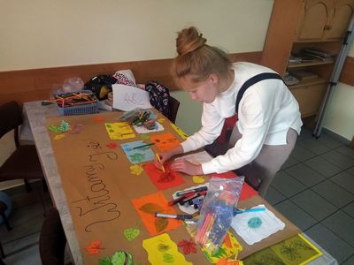Wychowanka Placówki Wsparcia Dziennego w Karwicach przygotowuje plakat dotyczący jesieni.