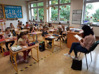 Mama Oli z klasy pierwszej Szkoły Podstawowej w Malechowie czyta fragment książki, a dzieci słuchają uważnie. 