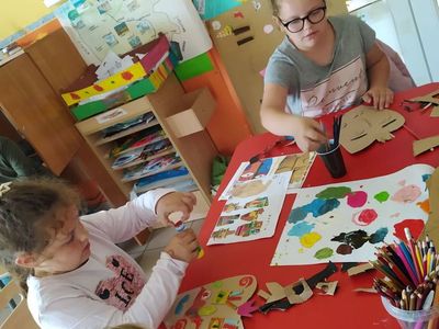 Dzieci z Placówki Wsparcia Dziennego w Laskach wykonują maski z tektury i kolorowych farb.