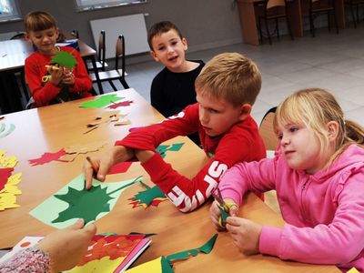 Dzieci z Placówki Wsparcia Dziennego w Kusicach wykonują jesienne liście.