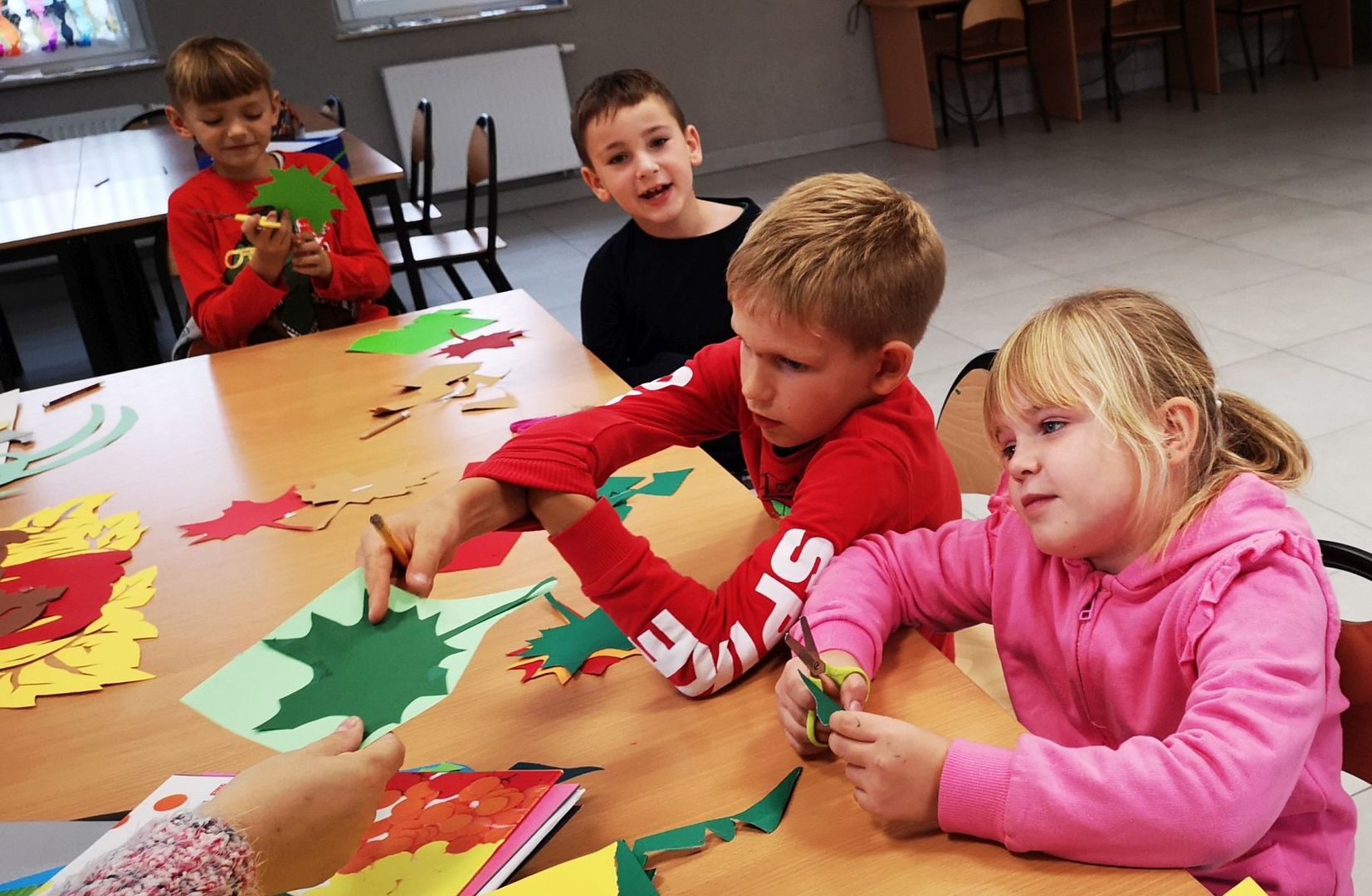 Dzieci z Placówki Wsparcia Dziennego w Kusicach wykonują jesienne liście.
