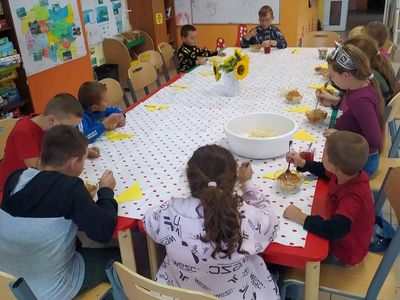Dzieci z Placówki Wsparcia Dziennego w Laskach siedzą przy stole i jedzą pomidorowe spaghetti.
