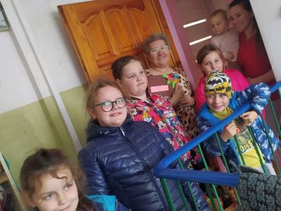 Dzieci z Placówki Wsparcia Dziennego w Laskach wręczają laurkę z okazji Dnia Seniora. 