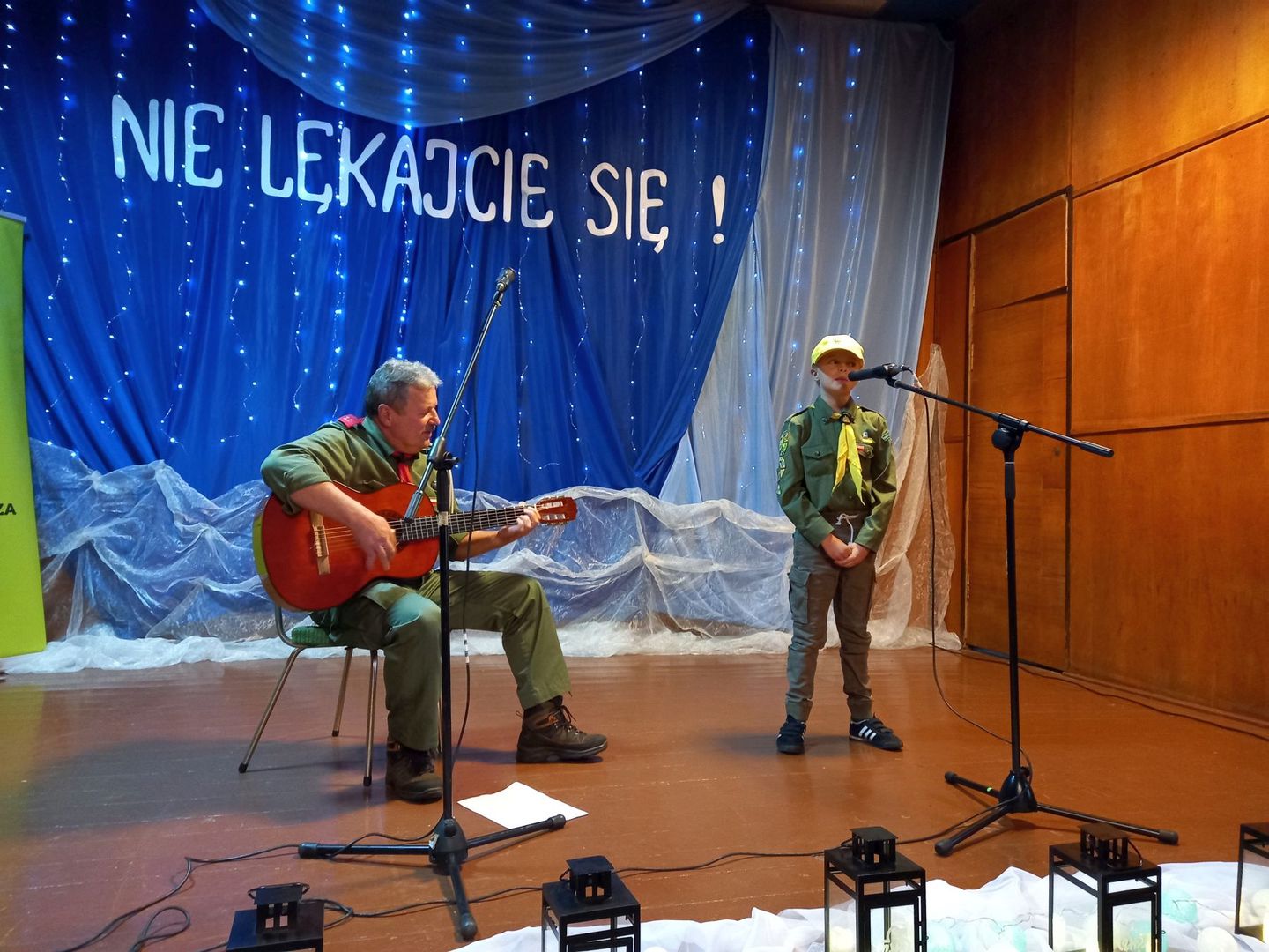 Na scenie druh Marek Jarosz gra na gitarze, obok niego śpiewająca harcerka.