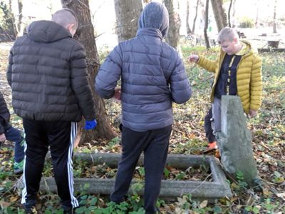 Wychowankowie Placówki Wsparcia Dziennego w Kosierzewie przy mogile na zabytkowym cmentarzu, porządkują teren. 