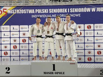 Grzegorz Babirecki na podium z brązowym medalem Mistrzostw Polski w judo, otoczonymi pozostałymi medalistami.  