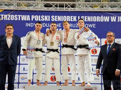 Grzegorz Babirecki na podium z brązowym medalem Mistrzostw Polski w judo, otoczonymi pozostałymi medalistami.  