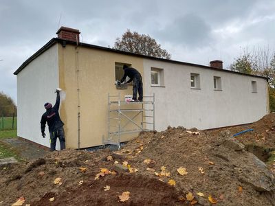Remontowany budynek hydroforni, dwie osoby malują ściany na zewnątrz. 