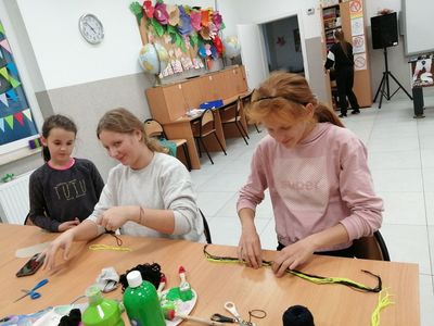 Trzy dziewczynki z placówki Wsparcia Dziennego w Kusicach przygotowują dekoracje przy użyciu włóczki.