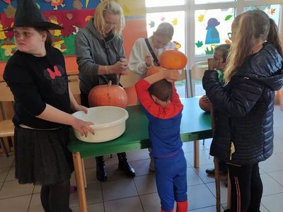 Dzieci z Placówki Wsparcia Dziennego z Lasek wraz z wychowawcą wykonują lampiony z dyni.