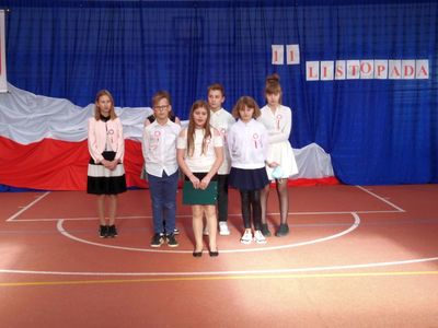 Uczniowie klasy piątej podczas występów w SP Lejkowo, dziewczęta i chłopcy występują na sali gimnastycznej.
