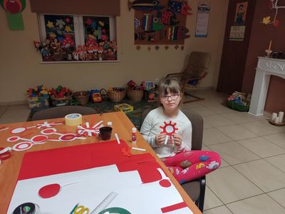 Dziewczynka z placówki wsparcia dziennego w Kosierzewie prezentuje wykonany kotylion.
