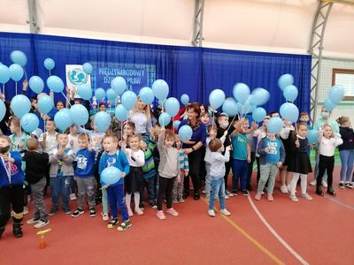 Niebieskie balony w rękach dzieci symbolizujące jedność z dziećmi na całym świecie, akcja w sali gimnastycznej SP Lejkowo, na zdjęciu nauczyciele i uczniowie.