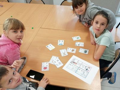 Dzieci z Placówki Wsparcia Dziennego w Kusicach pozują przy kartkach edukacyjnych.