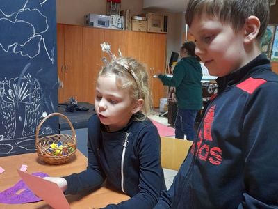 Dziewczynka i chłopiec z Placówki Wsparcia Dziennego w Sulechowie podczas odczytywania wróżb, w tle dziewczynka bawiąca się.