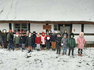 Grupa dzieci z Zespołu Szkolno - Przedszkolnego w Malechowie na tle zagrody edukacyjnej w Klukach.