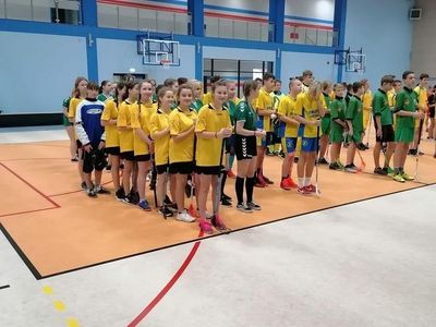 Drużyna dziewcząt w rzędzie na pierwszym planie, przed rozpoczęciem turnieju w unihokeja.