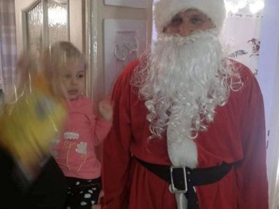 Święty Mikołaj i dziewczynka obdarowana słodkościami.