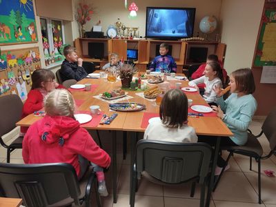 Dzieci z Placówki Wsparcia Dziennego w Kosierzewie przy stole podczas poczęstunku mikołajkowego.