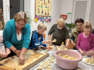 Panie z Klubu Seniora z Ostrowca lepią pierogi z dziećmi z Placówki Wsparcia Dziennego w ramach międzypokoleniowych warsztatów.