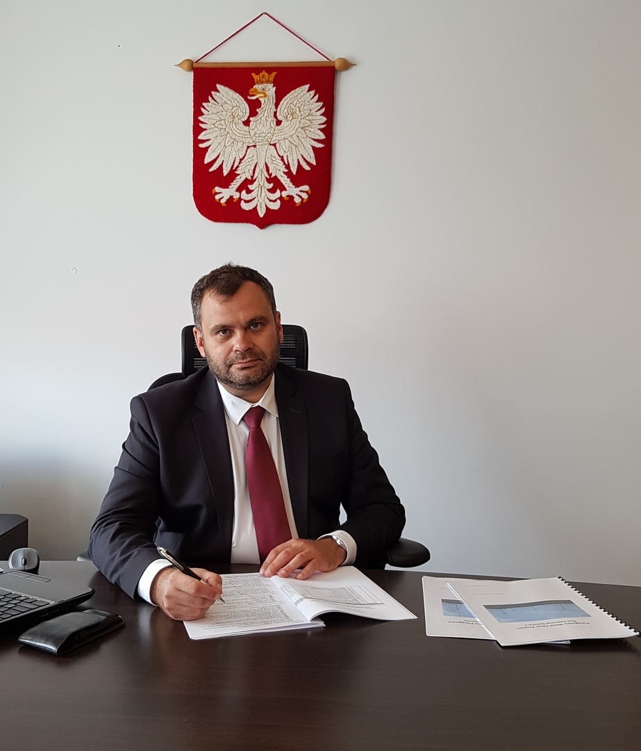 Wójt Radosław Nowakowski przy biurku w gabinecie.