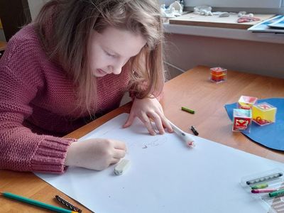 Dziewczynka z Placówki Wsparcia Dziennego w Sulechowie wykonująca rysunek na plakacie.