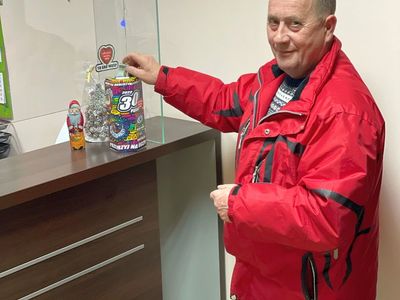 Strażak wrzucający pieniądze do skarbonki pozuje do zdjęcia. 