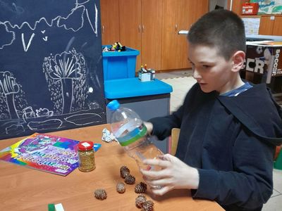 Chłopiec z Placówki Wsparcia Dziennego w Sulechowie podczas wykonywania karmnika z plastikowej butelki.