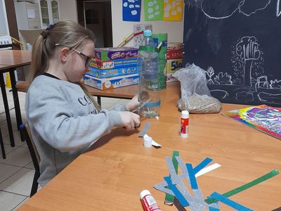 Dziewczynka z Placówki Wsparcia Dziennego w Sulechowie podczas wykonywania karmnika z plastikowej butelki.