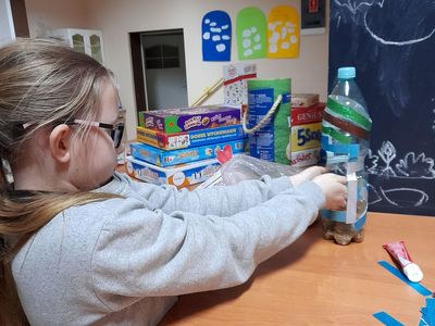 Dziewczynka z Placówki Wsparcia Dziennego w Sulechowie wykonująca karmnik dla ptaków z plastikowej butelki.