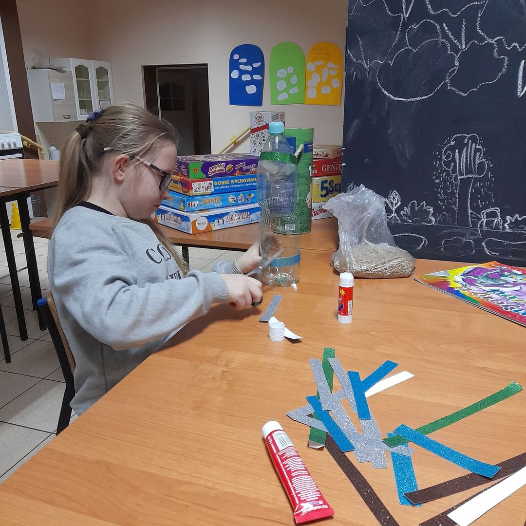 Dziewczynka z Placówki Wsparcia Dziennego w Sulechowie podczas wykonywania karmnika z plastikowej butelki.
