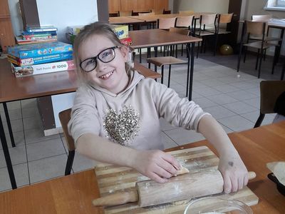 Dziewczynka z Placówki Wsparcia Dziennego w Sulechowie wałkująca ciasto.