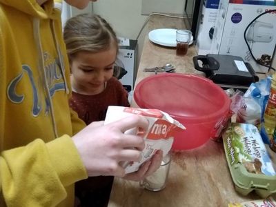 Dwie dziewczynki z Placówki Wsparcia Dziennego w Pękaninie przygotowują gofry, wsypują składniki do miski.