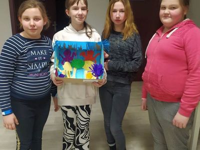 Dzieci z Placówki Wsparcia Dziennego z Lasek prezentują wykonane akwarium z papieru.