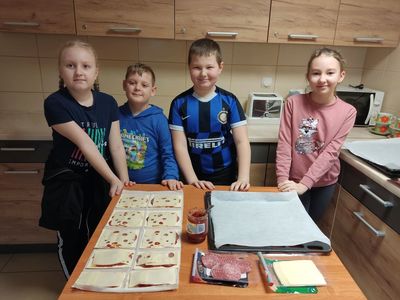 Dzieci z Placówki Wsparcia Dziennego w Kosierzewie prezentują wykonane minipizzetki gotowe do upieczenia.