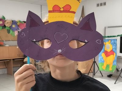 Dziewczynka z Placówki Wsparcia Dziennego w Kusicach prezentuje maskę karnawałową kota.