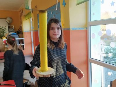 Wychowanka Placówki Wsparcia Dziennego w Laskach prezentuje tekturowy karmnik.