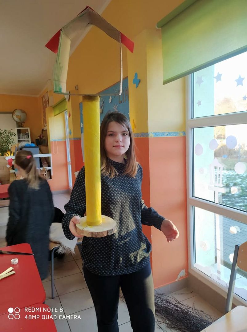 Wychowanka Placówki Wsparcia Dziennego w Laskach prezentuje tekturowy karmnik.