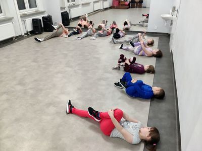 Trening breakdance w Świetlicy Kultury w Malechowie, dzieci rozciągają się z instruktorką.