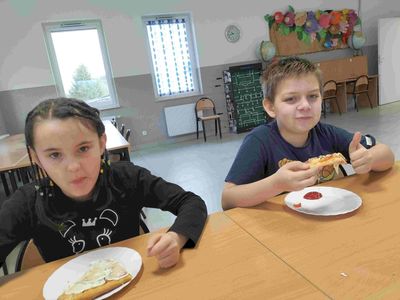 Chłopiec i dziewczynka z Placówki Wsparcia Dziennego z Kusic podczas jedzenia pizzy.