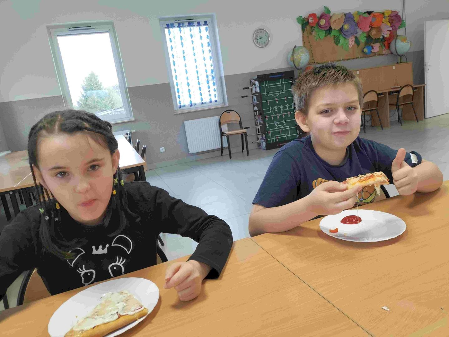 Chłopiec i dziewczynka z Placówki Wsparcia Dziennego z Kusic podczas jedzenia pizzy. 