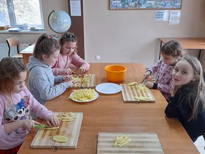 Dzieci z Placówki Wsparcia Dziennego w Sulechowie przygotowują ziemniaki, kroją je.