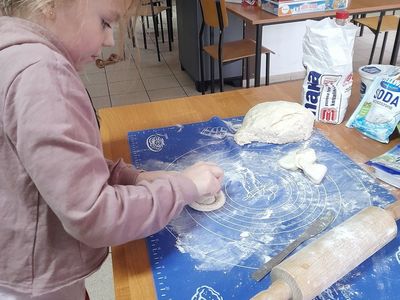 Dziewczynka z Placówki Wsparcia Dziennego w Sulechowie wykrawająca oponki serowe z ciasta.