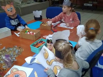 Wychowankowie z Placówki Wsparcia Dziennego w Pękaninie kolorują, wycinają i przyklejają puzzle kotków.