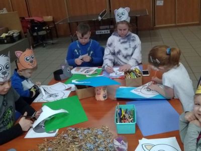 Wychowankowie z Placówki Wsparcia Dziennego w Pękaninie kolorują, wycinają i przyklejają puzzle kotków.