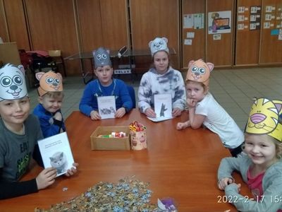 Wychowankowie z Placówki Wsparcia Dziennego w Pękaninie pozują w kocich opaskach z fotografiami kotów. 