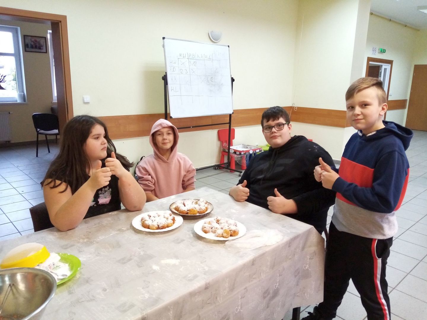 Dzieci z Karwic pozują z minipączkami przy stole, które samodzielnie wykonały.