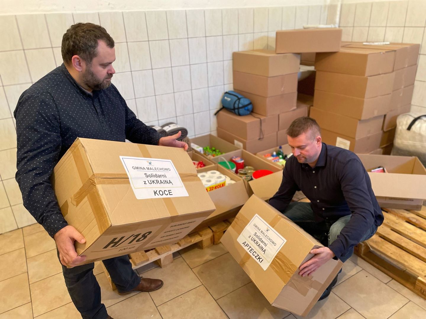 Wójt Radosław Nowakowski i Kierownik Referatu Organizacyjno-Administracyjnego Damian Dul podczas przygotowywania paczek.
