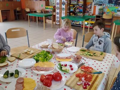 Dzieci z Placówki Wsparcia Dziennego z Lasek robią kanapki z warzywami, wędliną i serem.